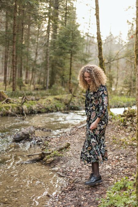 Portrait Nadja Jeannine vor einem Bach im Wald.