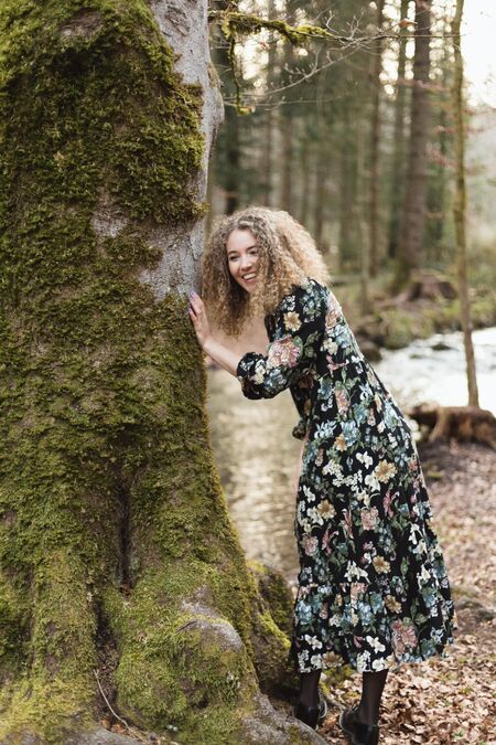 Portrait Nadja Jeannine stützt sich an einem grossen Baum.