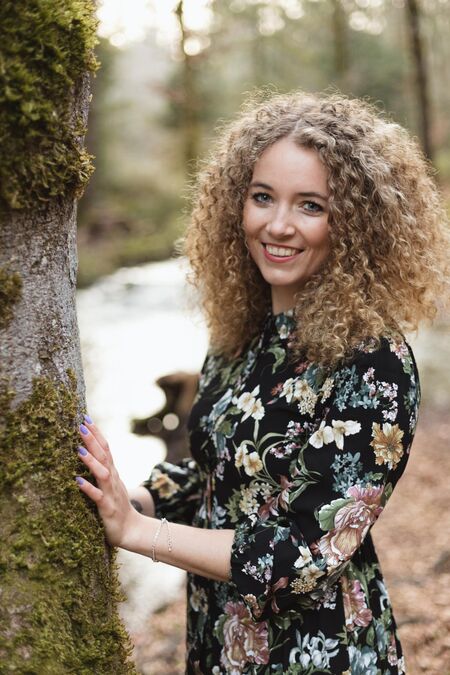 Portrait Nadja Jeannine stützt sich an einem grossen Baum.